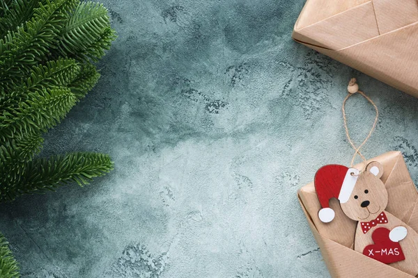Regalos de Navidad en papel artesanal y rama de abeto sobre un fondo verde texturizado. — Foto de Stock