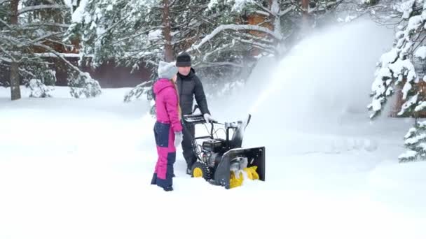 Father and daughter in winter in yard of country house remove snow with snowplow — стоковое видео
