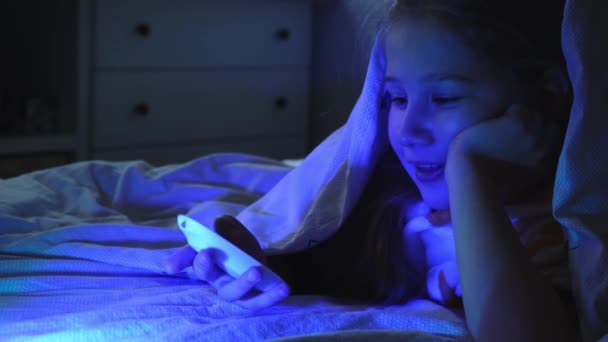 Portret wesołej dziewczyny podczas oglądania telewizji w nocy pod kocem. — Wideo stockowe