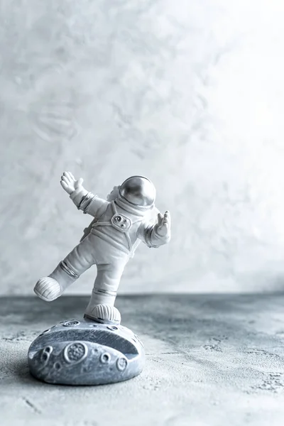 Miniatura astronauta balanceamento na lua em traje espacial em fundo texturizado cinza. — Fotografia de Stock