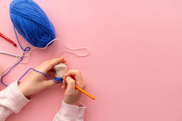 Las manos de los niños en el proceso de ganchillo juguetes de hilo azul y beige. —  Fotos de Stock