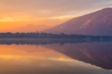 Dramatik Ateş kırmızı bulutları alacakaranlık gökyüzünde sürükleniyor günbatımından hemen sonra Como, Lombardy, İtalya gölüne yansıyor.