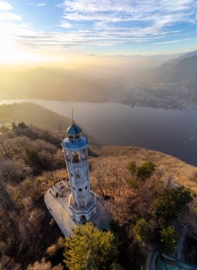 Günbatımı ışığıyla Como Gölü 'nün ufuk çizgisi üzerinde bir deniz fenerinin insansız hava aracı görüntüsü - Faro Voltiano (Volta Deniz Feneri) - Seyahat Hedefi, Brunate, Como, Lombardy, İtalya