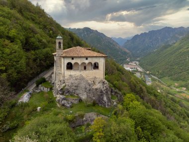 Aerial panoramic view from the drone of the Sanctuary of St. Patrick (San Patrizio) built on the sheer cliff, Colzate, Bergamo, Italy