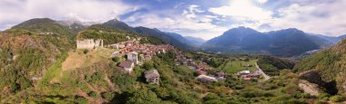 Stunning panoramic landscape of a village and old ruins located next to a cliff in the mountain - Aerial View - Cimbergo, Lombardy, Italy