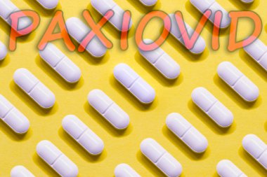 Paxiovid. Pfizer antiviral against Covid-19 (Coronavirus). Revolutionary pills for Covid. Background with pills on yellow background. Horizontal photography. Design with text.