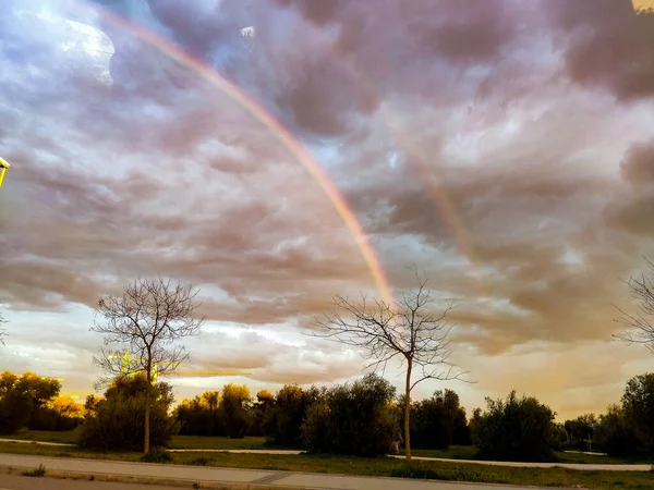 Rainbow. Colorful rainbow in the sky of Valdemoro at sunset, coinciding the rain with the sun. Cloudy sky. Horizontal photography.