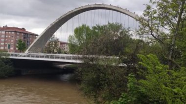 Nehir. Arga Nehri, Pamplona, Navarra 'dan geçerken. Köprüden geçen bir nehir. Bulutlu bir gün. Yatay video.