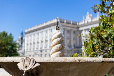 Çeşme. Su dolu taş çeşme. Arka planda Kraliyet Sarayı odak dışı. Madrid 'de açık bir günde, İspanya' da mavi gökyüzü olan bir parkta. Avrupa. Fotoğraf:.