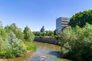 Madrid Rio Parkı. Manzanares nehrinin yanındaki Madrid Rio Parkı manzarası ve çevresindeki yeşil bitki örtüsü. Köprüleri ve yaya köprüleri olan yollar. İspanya 'da su püskürten fıskiyeler. Avrupa. Fotoğraf:.