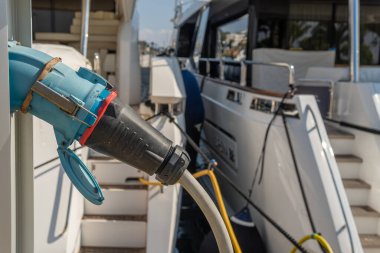 Lüks yatı olan ve elektriğe bağlı bir kabloyla elektrik alan bir elektrik santraline yakın plan. Puerto Portalları, Mallorca Adası, İspanya