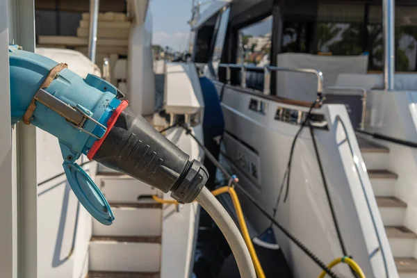 Lüks yatı olan ve elektriğe bağlı bir kabloyla elektrik alan bir elektrik santraline yakın plan. Puerto Portalları, Mallorca Adası, İspanya