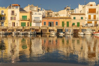 Portocolom, İspanya; Ekim 05: 2021: Gündoğumunda Meiterranean Denizi 'nde demirli ve yansıtılan geleneksel iskelenin genel görünümü. Mallorca Adası, İspanya