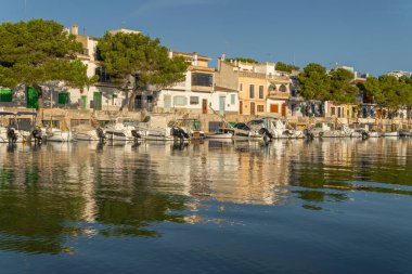 Portocolom, İspanya; Ekim 05: 2021: Gündoğumunda Meiterranean Denizi 'nde demirli ve yansıtılan geleneksel iskelenin genel görünümü. Mallorca Adası, İspanya