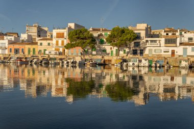 Portocolom, İspanya; Ekim 05: 2021: Gündoğumunda Meiterranean Denizi 'nde demirli ve yansıtılan geleneksel iskelenin genel görünümü. Mallorca Adası, İspanya