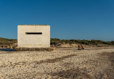 Es Trenc, İspanya; 11 Ekim 2021: İspanya iç savaşının eski sığınağı Es Trenc sahilinde, gün batımında, banyocuların yanında. Mallorca Adası, İspanya