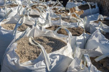 Yan yana yığılmış beyaz inşaat enkazı torbaları.