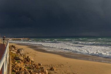 Palma de Mallorca, İspanya; 08 Aralık 2021: Palma de Mallorca şehrinde Pere Antoni plajı, gün batımında rüzgarlı bir sonbahar fırtınası olan manzarayı izleyen bir adamla birlikte olabilir mi? Muhteşem manzara.