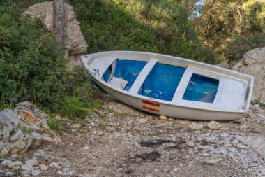 İspanya 'nın Mallorca adasındaki kayalık bir körfezde karaya oturmuş bir eğlence teknesi. Mallorca adasındaki düşük turist yoğunluğunun görüntüsü