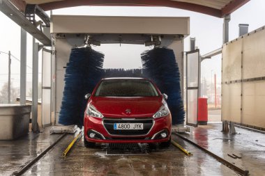 Campos, İspanya; 30 Aralık 2021: Kırmızı Peugeot 208 model araba bir oto yıkama tünelinde temizleniyor
