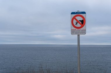 Palma de Mallorca, İspanya; Ocak 02 2022: İspanyolca, Katalanca ve İngilizce yazılan ve uçurumdan atlamayı yasaklayan bir tabelanın yakın çekimi. Arka planda, Akdeniz odak dışı.