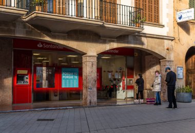 Llucmajor, İspanya; Ocak 07 2022: Banco Santander şubesi, İspanya 'nın Llucmajor kentinde, maske takan ve sırada bekleyen insanlarla birlikte. Yeni normal kavram