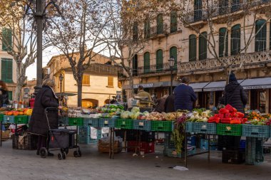 Llucmajor, İspanya; Ocak 07 2022: Majorcan kasabasındaki haftalık sokak pazarı. Coronavirus 'un Omicron versiyonunun kısıtlamalarından dolayı maskeli tedarikçiler ve müşteriler. Yeni normal