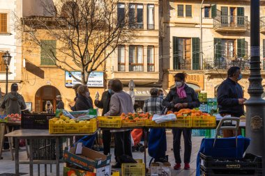 Llucmajor, İspanya; Ocak 07 2022: Majorcan kasabasındaki haftalık sokak pazarı. Coronavirus 'un Omicron versiyonunun kısıtlamalarından dolayı maskeli tedarikçiler ve müşteriler. Yeni normal