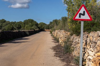 Güneşli bir günde Mallorca adasında bir köy yolunda tehlikeli bir kavis işareti