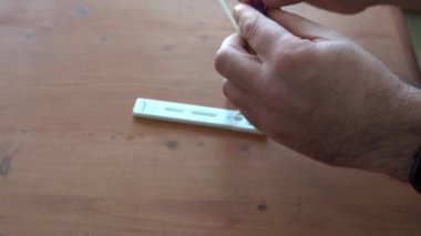 Evde antijen testi yapan ellerin yakın çekimi.
