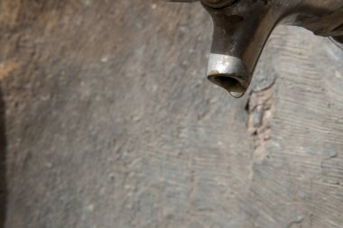 Metal bir musluğun bir damla suyla yakın çekimi. Su ve kuraklığın kavramsal görüntüsü