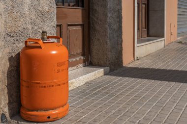 Felanitx, İspanya; Mart 07 2022: Bir evin kapısındaki boş bütan tüpü, bütan adamının gelip yenisini getirmesini bekliyor. Petrol ve doğalgaz krizinin kavramsal görüntüsü