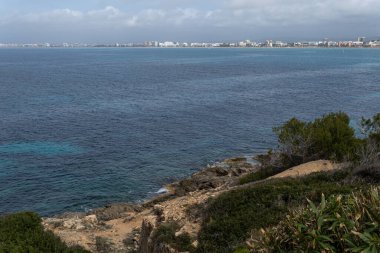 Mallorca adasının kayalık kıyı şeridi manzarası, arka planda Palma de Mallorca şehri, İspanya