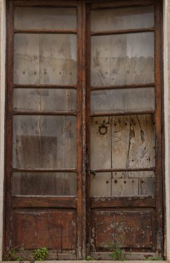 Terk edilmiş ve harabeye dönmüş bir evin ahşap ve cam kapısına yakın çekim. İspanya 'nın kırsal kesimlerinde terk edilmiş evler