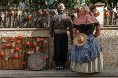 Porreres, Spain; june 04 2022: Annual apricot fair held in the Majorcan town of Porreres, Spain. Street decoration with sculptures of farm workers and their harvesting of apricots clipart