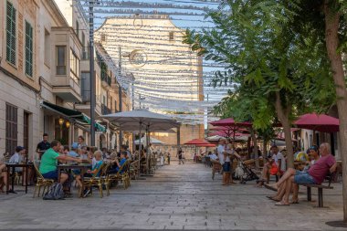 Santanyi, Spain; july 30 2022: Main street of the Mallorcan town of Santanyi, full of terraces of cafes and restaurants with customers at sunset