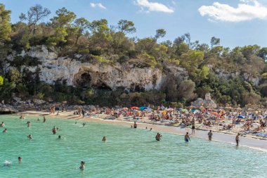 Cala Llombards, İspanya; 23 Eylül 2022: Akdeniz kıyısında güneşlenen ve plajda yüzen turistlerin olduğu genel manzara. Mallorca Adası, İspanya