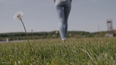 Özgür bir kız çiçeğin arka planında çıplak ayakla yürüyor.