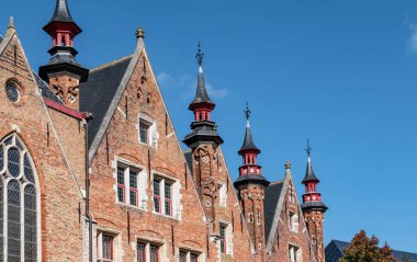Şehir merkezindeki Bruges binalarının Gotik çatıları. Huidenvettersplein, Buges, Belçika 'daki tuğla duvar cephelerinin perspektifi azalıyor.