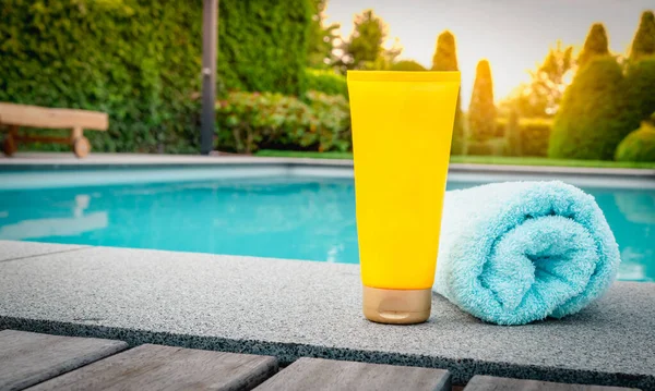 Skin care and protection against harmful sun rays. Yellow tube of sunscreen at the swimming pool.