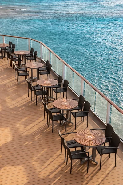 Outdoor furniture on cruise ship. Empty tables and chairs on deck.
