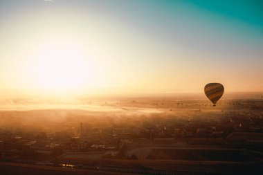 Beautiful wide view of a single hot air balloon during a balloon ride in luxor egypt. Hot air balloons very popular with tourist areas such as cappadocia clipart