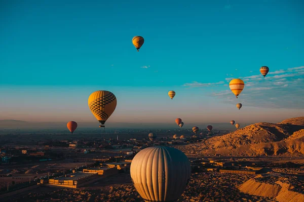 Lüks Mısır bölgesinde uçuşan düzinelerce sıcak hava balonunun geniş görüşü. Popüler turistik etkinlik, etrafındaki çöl manzarası inanılmaz.