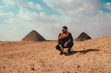 Saqqara Piramitleri 'nde çölde poz veren turist bir adamın, şimdiye kadar inşa edilen ilk piramitler olduğuna inanılıyor. Mısır 'da soğuk kış günü