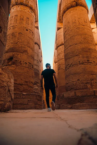 エジプトの豪華な寺院の巨大な柱の周りを歩く観光客の垂直ショット 古代エジプトの柱は何千年も後にここに立ち 人々が訪れることができます — ストック写真