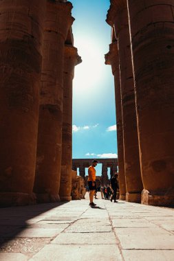 Lüks Mısır Ocak 2022 Mısırdaki Luxor Tapınağı 'nın büyük sütunları arasında duruyor. Antik uygarlığı takdir eden bir turist bölgeyi ziyaret ediyor.
