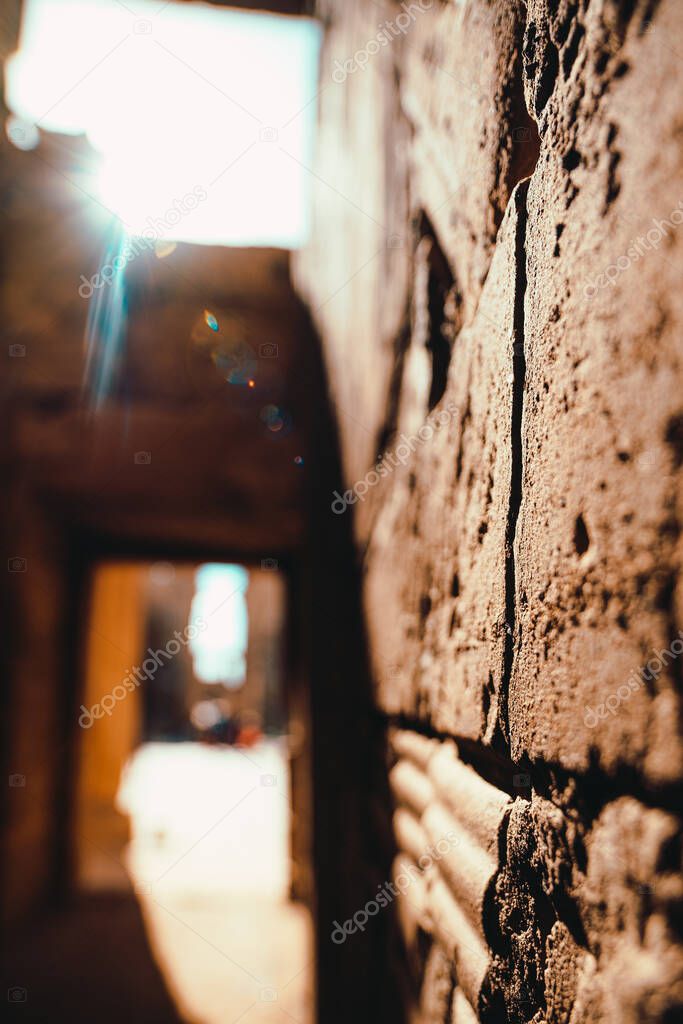 Close focus on a wall in a temple in egypt, ancient stone walls and pillars. Harsh sun shining straight into the lens