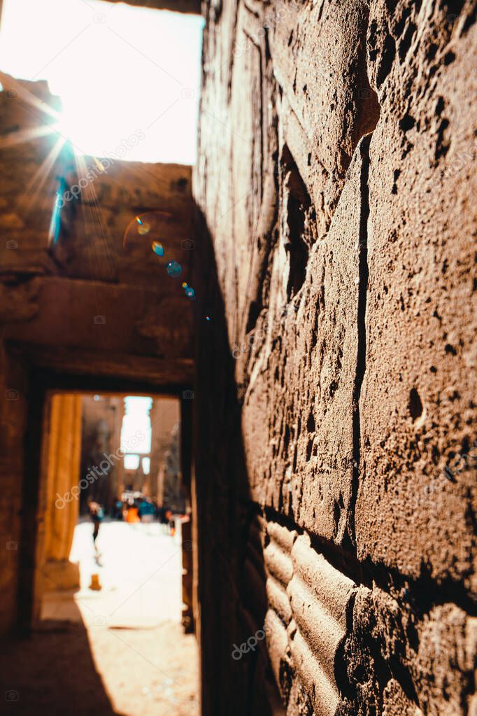 Close focus on a wall in a temple in egypt, ancient stone walls and pillars. Harsh sun shining straight into the lens