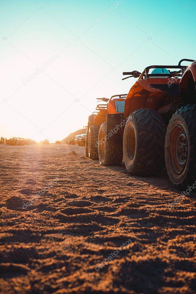View of several atv quad bikes parked inline in the middle of a desert near hurghada. Sunset hour with the sun shining straight at the camera
