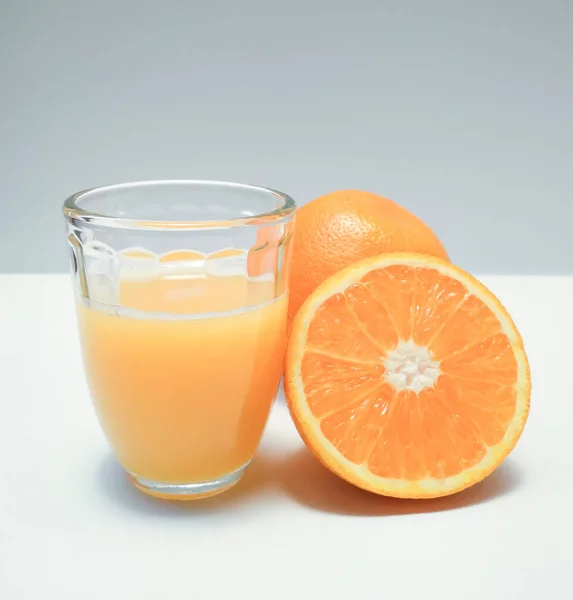 glass with orange drink and halved orange